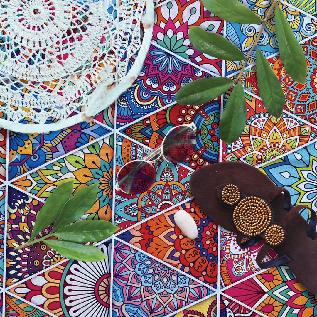 Shoes, glasses, a white dreamcatcher on top of colourful fun sand-free  towel with leaves and a shell