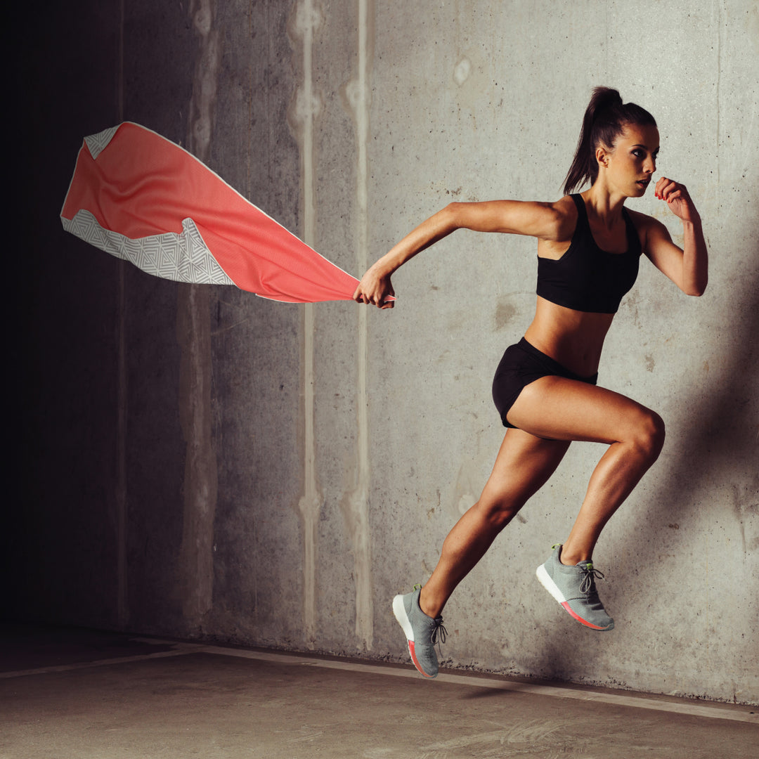 action shot of women in midair holding a vibrant coral color eco-friendly gym towel