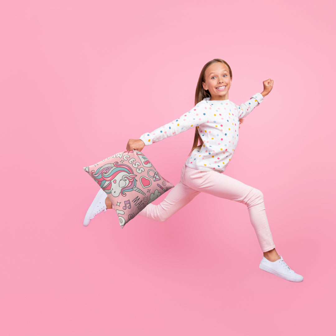 Happy girl leaping and holding beauiful sensory princess cushion with a unicorn on it. 