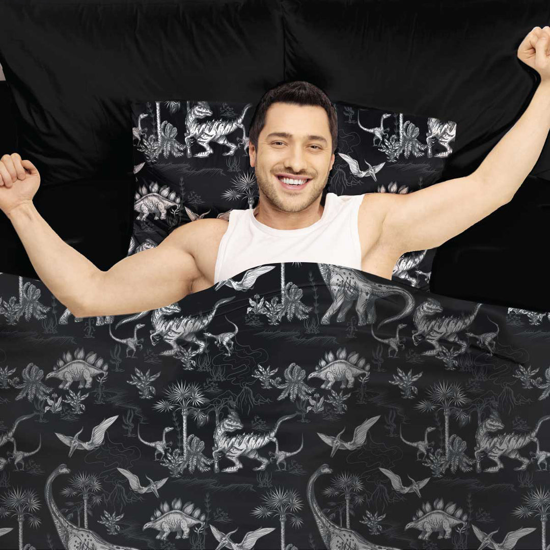 Man in bed stretching with Dinosaur sensory Compression sheets and matching pillowcase by JettProof