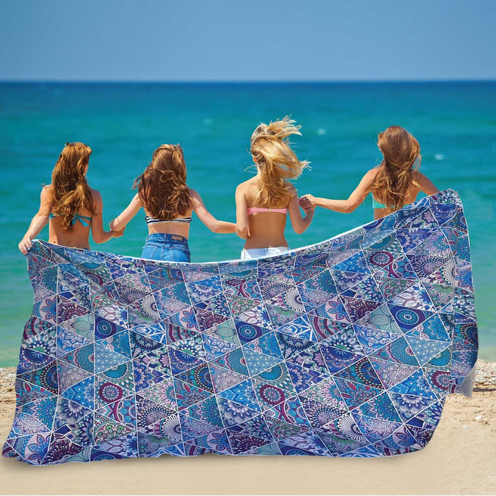 four girls running on beach with oversized sand free towel 