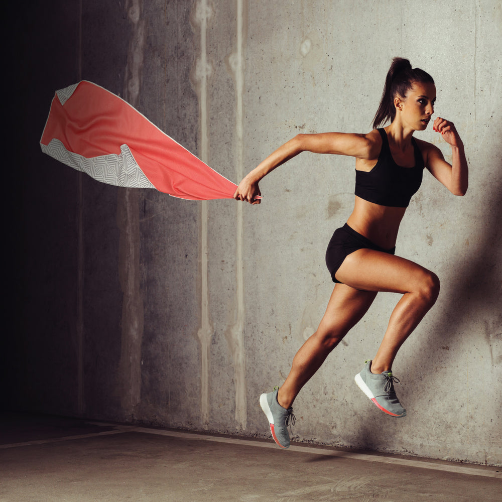 action shot of women in midair holding a vibrant coral color eco-friendly gym towel