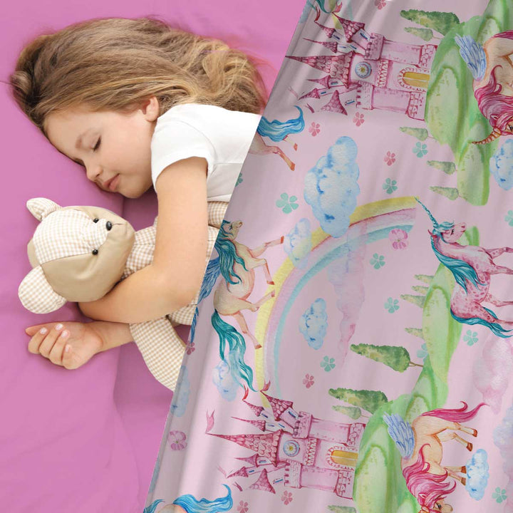 young girl sleeping in bed with pink fitted sheets and matching unicorn rainbow and castle print compression sheets by JettProof