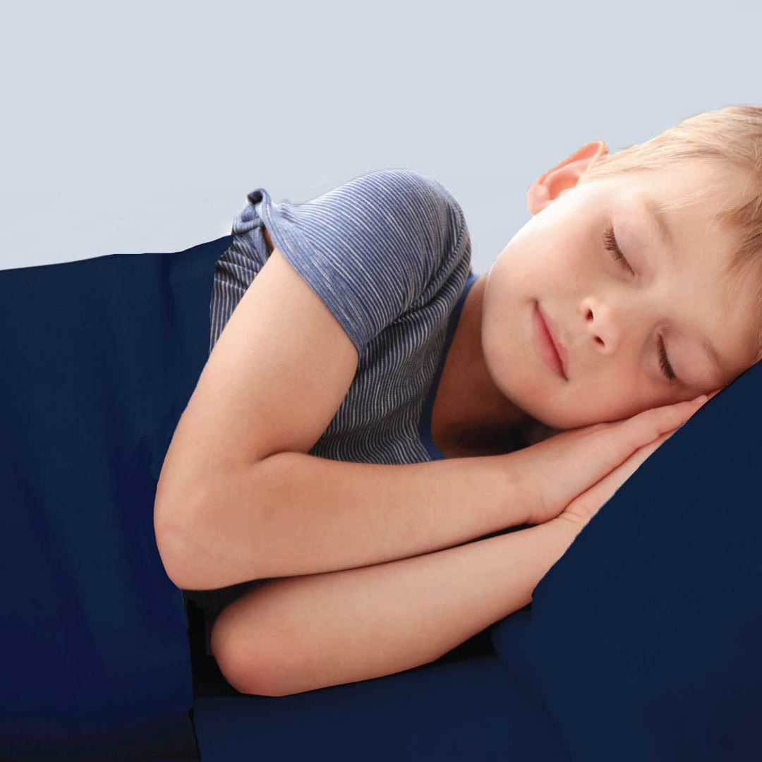 Boy calm in bed asleep in Navy Calming compression sheets by JettProof