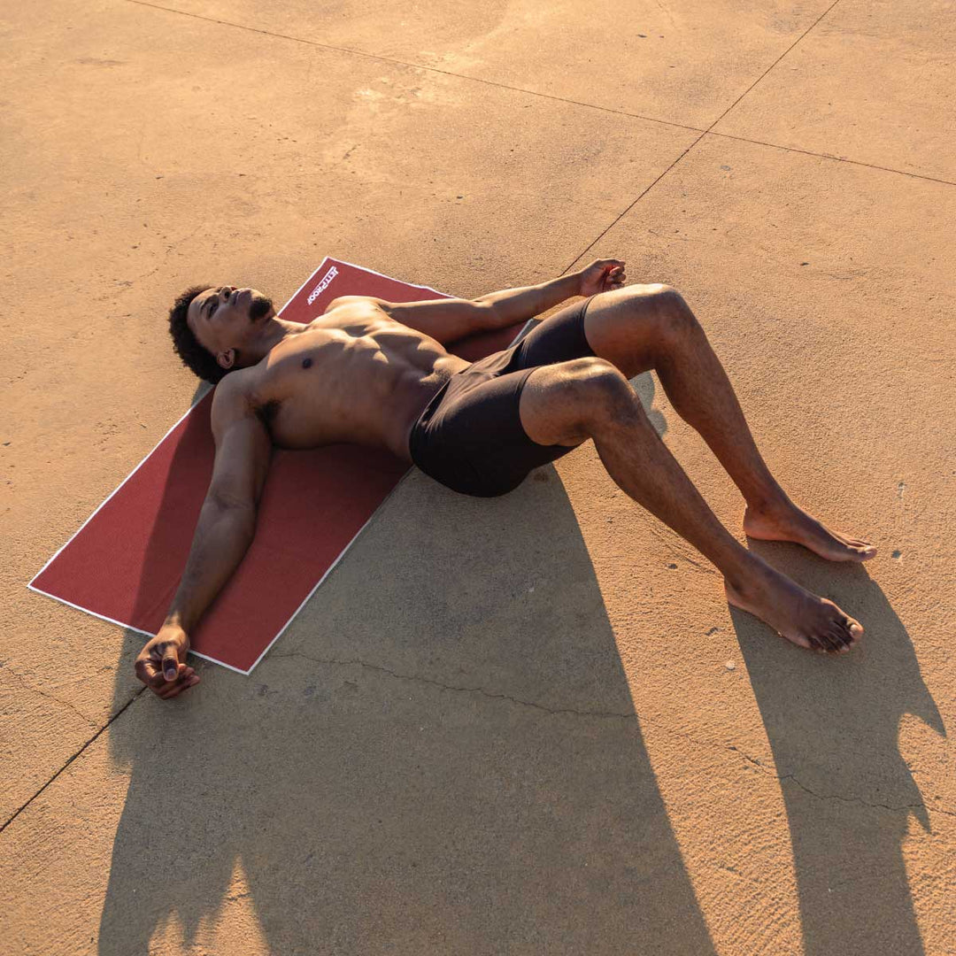 Man resting on burgundy antibacterial Gym towel