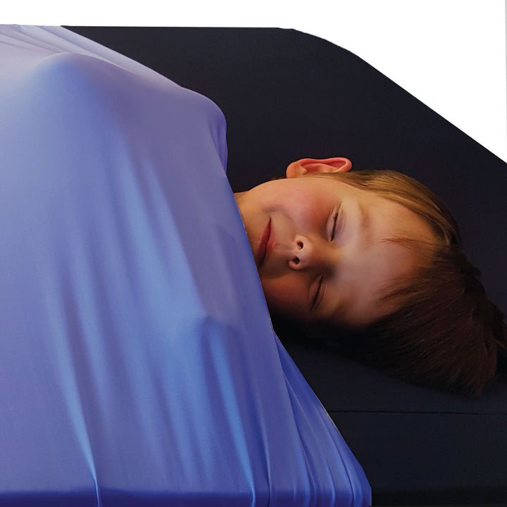 Young boy asleep in cornflower blue calming compression sheets