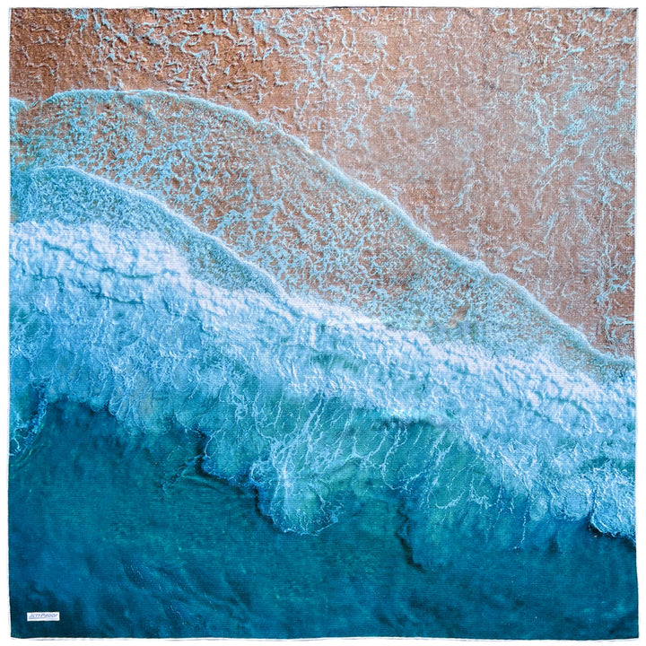Laid out oversized sand-free towel Featuring an aerial image of a beautiful beach with waves crashing on coast
