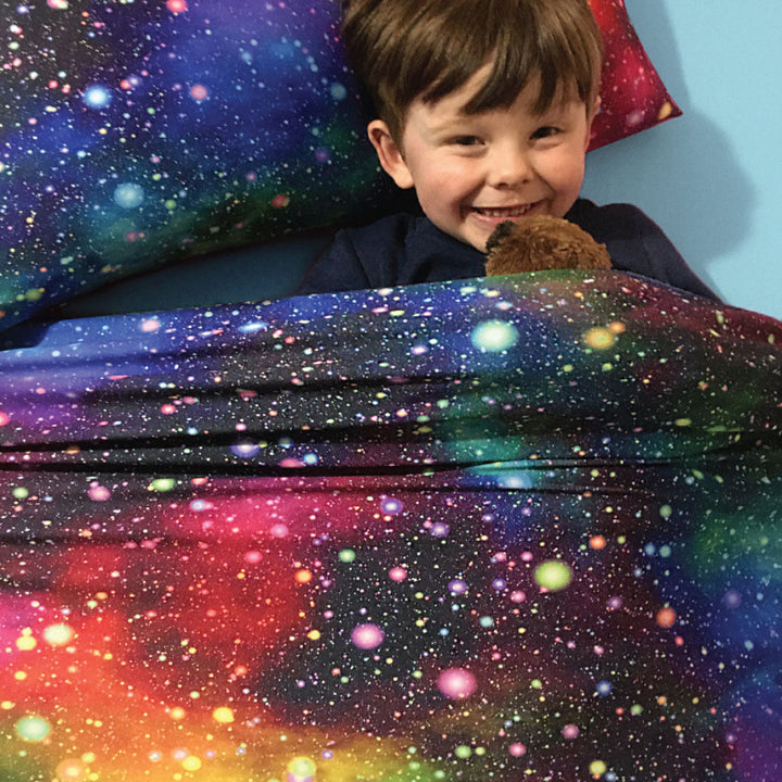 Child in sensory compression sheets with beautiful rainbow star patterns and matching pillowcase
