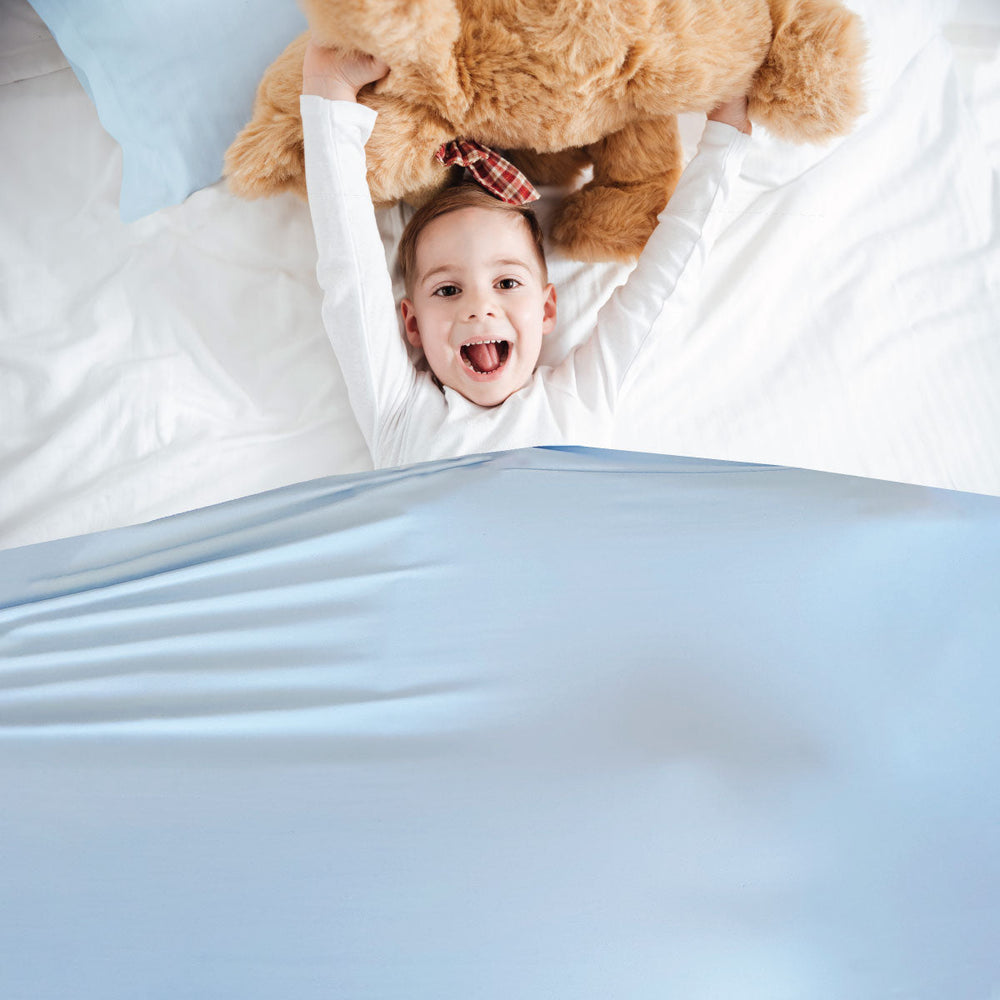 Little boy happy in light blue calming compression sheets 