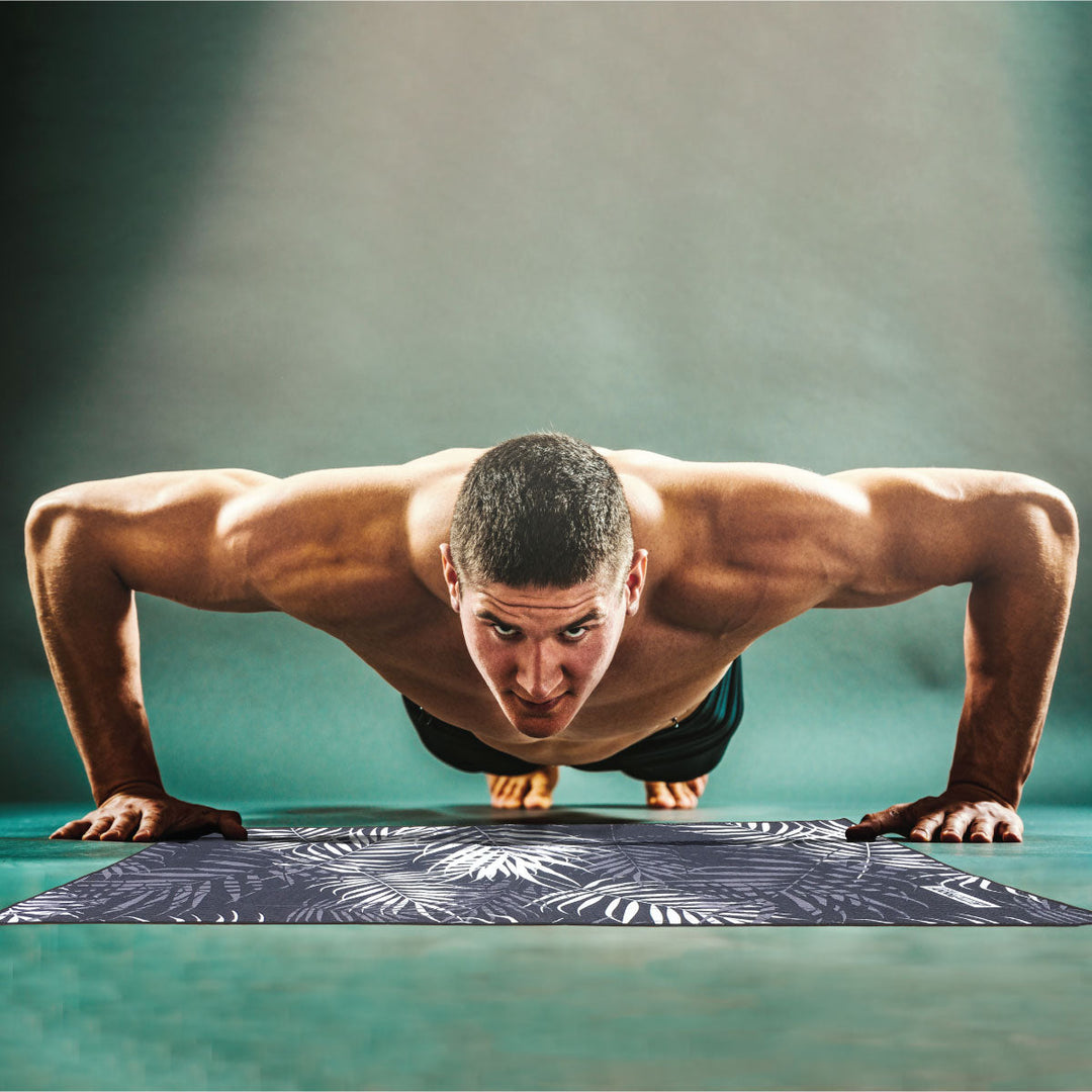 Man doing push up on an antibacterial gym towel with black and white leaves by JettProof
